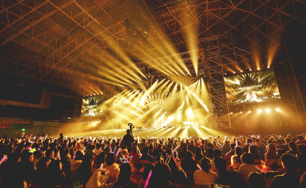 Dynamic concert scene with vibrant crowd and dazzling stage lights indoors.